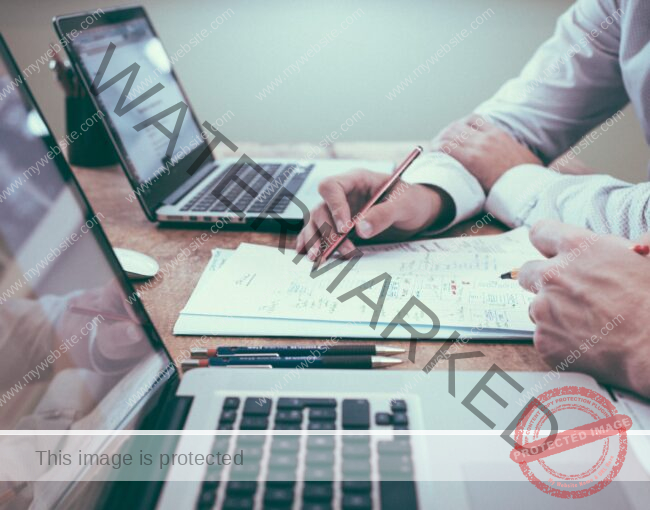 person holding pencil near laptop computer
